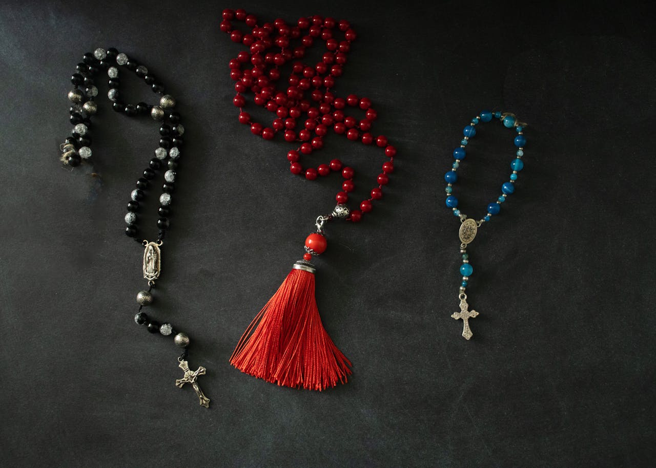Flat lay of decorative rosaries and prayer beads on a dark background, highlighting spirituality and faith.
