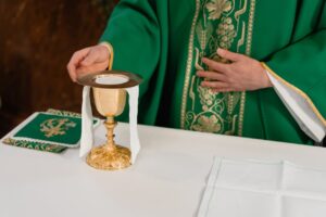 Close-up of a priest's hand arranging communion elements during a religious ceremony indoors.