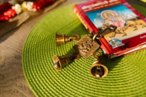 Close-up of religious symbols including golden bells and a book on a green placemat.